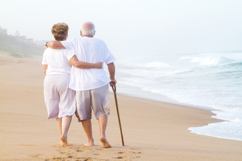 elderly couple walking on beach